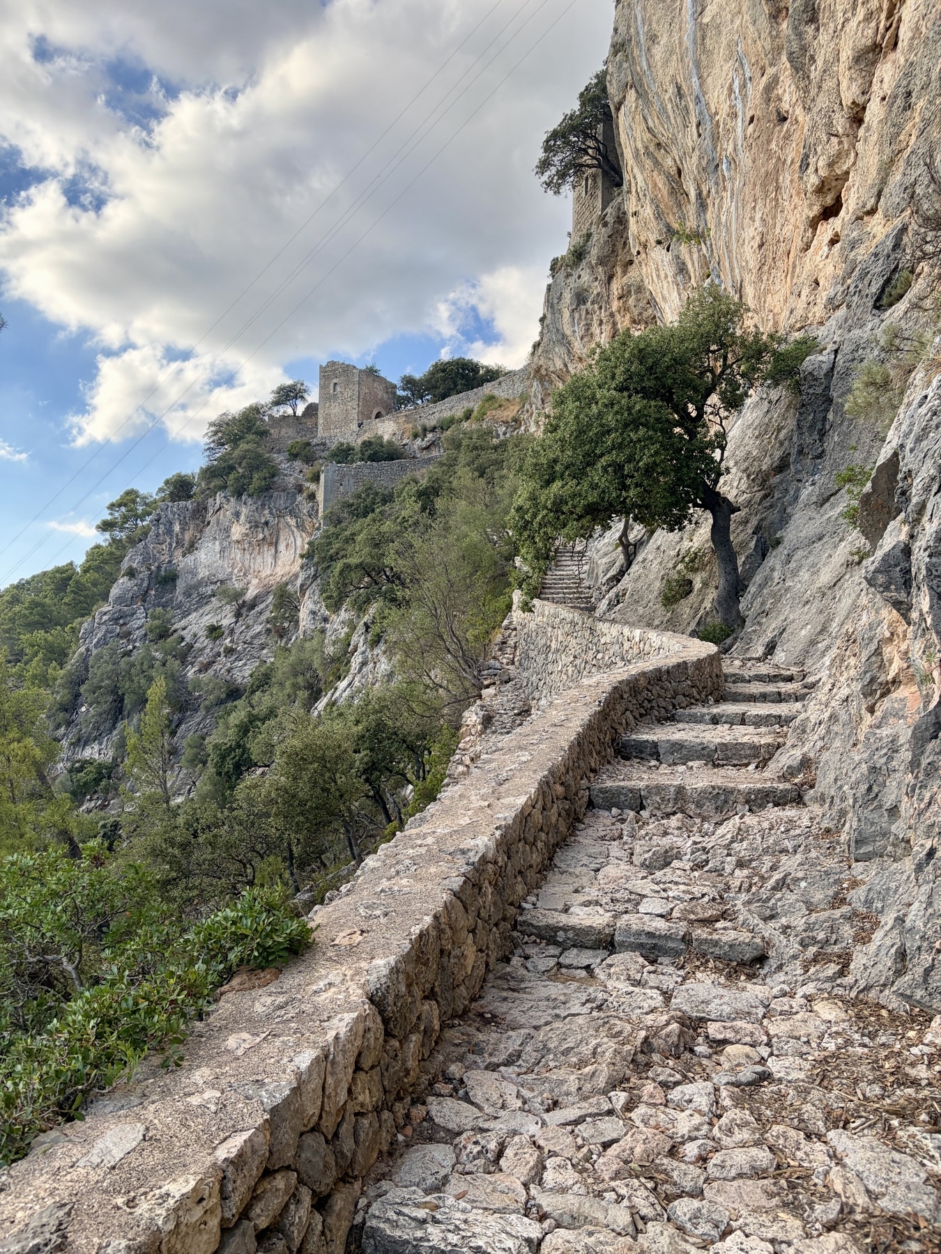 El camino de piedra alcanza el Castell d’Alaró junto a la pared de roca