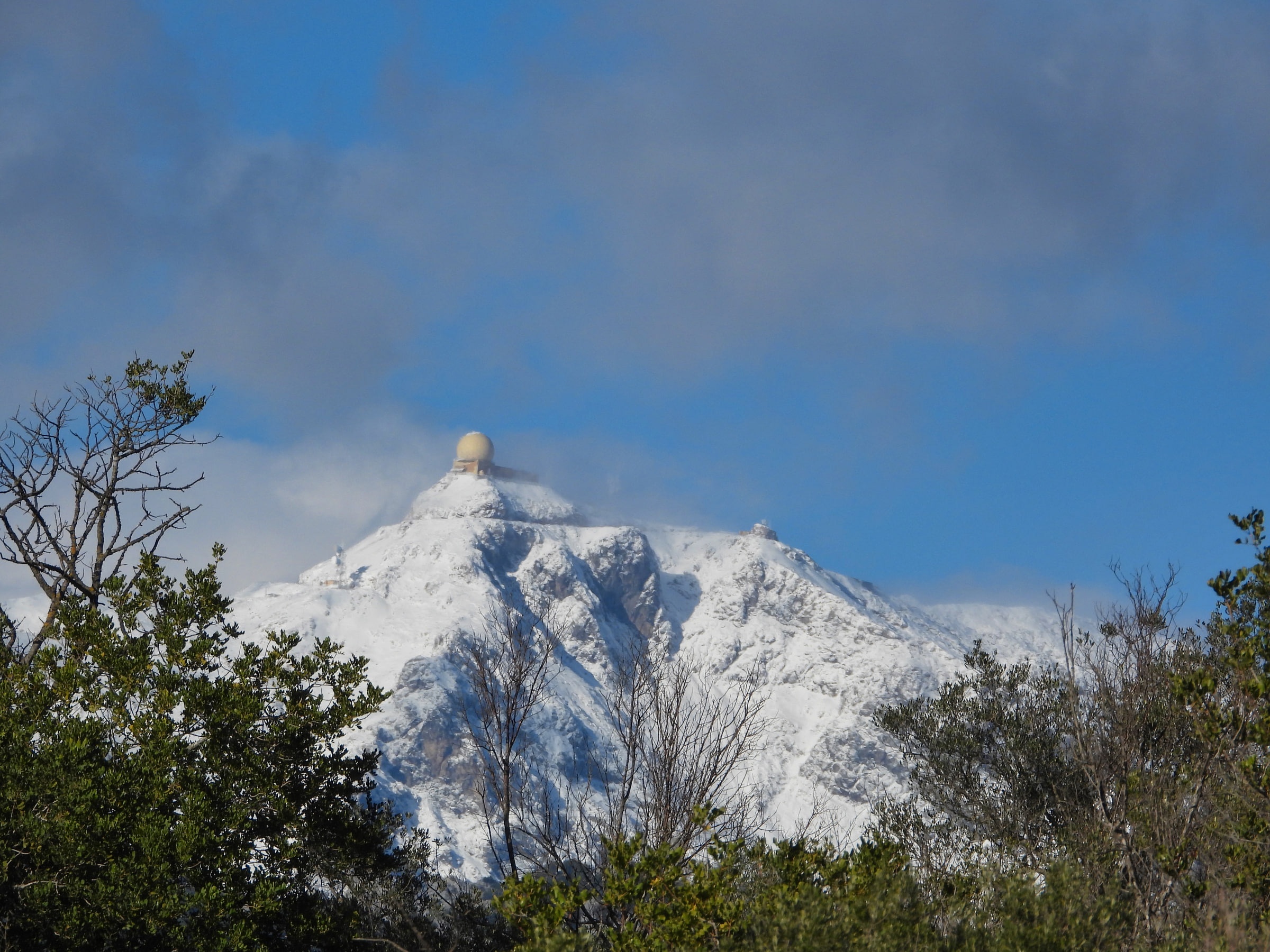 Cumbre nevada entre nubes, coronada por una cúpula